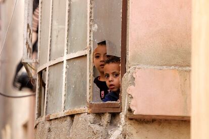 Niños palestinos miran a través de una ventana a los soldados israelíes que realizan redadas en el campo de refugiados de Al-Fawwar, al sur de la ciudad cisjornada de Hebrón (Palestina).