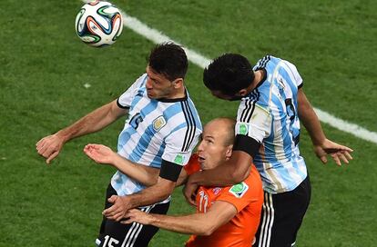 Los argentinos Martin Demichelis (i) y Ezequiel Garay (d) se disputan un bal&oacute;n con el delantero holand&eacute;s Arjen Robben, en en centro.