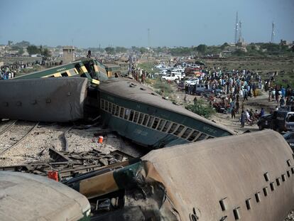 Funcionarios de seguridad y rescate de Pakistán inspeccionan los vagones de un tren que ha descarrilado en el sur de Pakistán, este domingo.