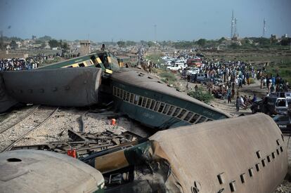 Funcionarios de seguridad y rescate de Pakistán inspeccionan los vagones de un tren que ha descarrilado en el sur de Pakistán, este domingo.