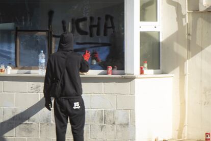 Un manifestante escribe con espray la palabra "Lucha" en la puerta de Navantia.