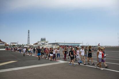 Un grupo de viajeros atraviesa la pista de aterrizaje del aeropuerto de Gibraltar.