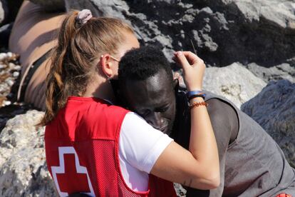 Una cooperante de Cruz Roja conforta a un migrante que cruzó uno de los espigones fronterizos de Ceuta, el 18 de mayo.