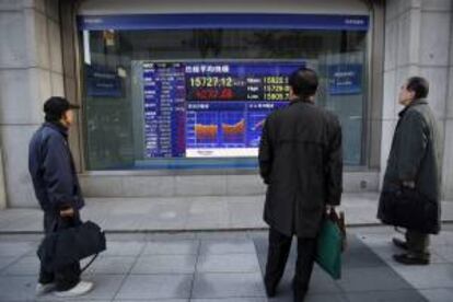 Varios viandantes observan una pantalla que muestra el valor alcanzado por el índice Nikkei en la Bolsa de Tokio. EFE/Archivo
