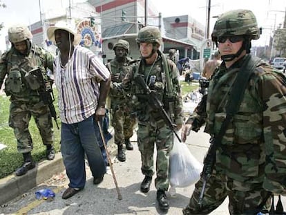 Varios miembros de la Guardia Nacional ayudan a uno de los supervivientes de la catástrofe en Nueva Orleans.