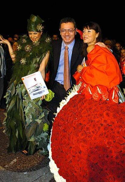 El alcalde de Madrid, Alberto Ruiz Gallardón, acompaña a dos mujeres que lucen vestidos hechos con flores, traídas de Holanda, en la madrileña Plaza de Colón, durante la celebración de la Noche en Blanco.