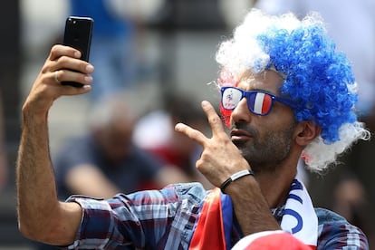 Un aficionado se hace un selfie con una peluca y unas gafas con los colores de Francia. 
