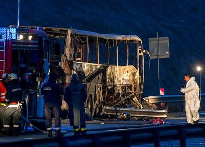Bomberos, policías e investigadores inspeccionan los restos de un autobús que se incendió en una carretera, causando la muerte de al menos a 45 personas, cerca del pueblo de Bosnek, Bulgaria.