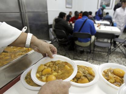 Voluntarios del comedor Cuatro Caminos, en Madrid, sirven comidas.