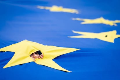 A child peeks out of a hole in a European flag in February in Bucharest.