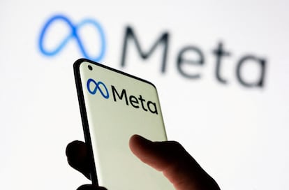 Una mujer sostiene un teléfono inteligente con el logotipo de Meta frente al nuevo logotipo de cambio de marca de Facebook.