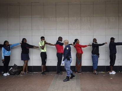 Un policía comprueba que los ciudadanos que están en la cola de un supermercado respetan la distancia de seguridad en Johanesburgo, Sudáfrica, el 28 de marzo.