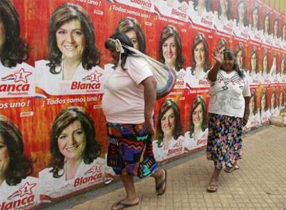 Dos mujeres guaraníes pasan junto a carteles de la líder del Partido Colorado, Blanca Ovelar, en Asunción.