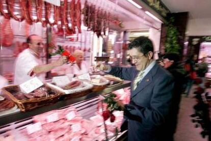 Patxi López entrega una rosa a un carnicero del mercado del barrio de Zaramaga, en Vitoria.