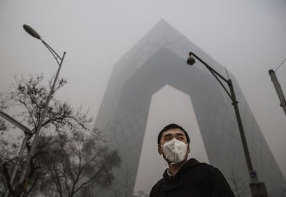 Un hombre chino lleva una máscara de protección a su paso por el edificio de la CCTV en un día de fuerte contaminación en Beijing.