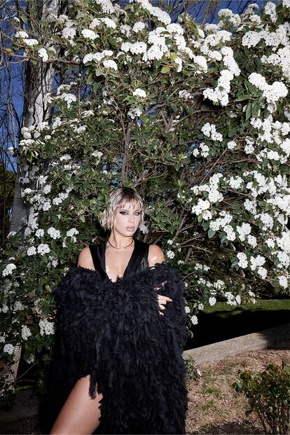 La cantante Nathy Peluso, con abrigo y vestido corto con capucha y cuello desbocado, todode VERSACE, y collar Juste un Clou en oro amarillo de CARTIER.