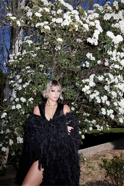 La cantante Nathy Peluso, con abrigo y vestido corto con capucha y cuello desbocado, todode VERSACE, y collar Juste un Clou en oro amarillo de CARTIER.