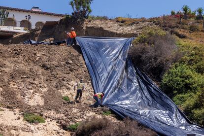 Trabajadores cubren con plástico una colina llena de toboganes para protegerla de las fuertes lluvias que se esperan, en California, Estados Unidos.