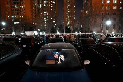 Varias personas esperaban en su coche para ver los fuegos artificiales de la ceremonia de clausura de los Juegos Olímpicos de Invierno 2022 en el Estadio Nacional de Pekín.