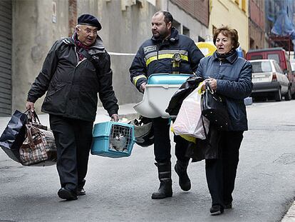 Afectados por el hundimiento del Carmel salen de recoger enseres de sus domicilios acompañados por un bombero.