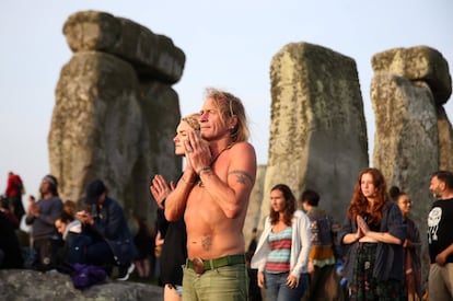 Un hombre y una mujer meditan mientras reciben los rayos del sol en el solsticio de verano.