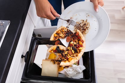 Una persona tira restos de comida a la basura en un domicilio.