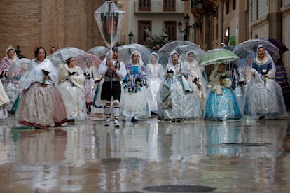 Un grupo de falleras desfilaba este martes protegido de la lluvia con paraguas durante la ofrenda de flores a la Virgen de los Desamparados, el acto más multitudinario de las Fallas de Valencia.