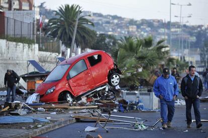 Dos hombres caminan frente a un vehículo arrastrado por el tsunami posterior al terremoto 8,4 en la escala de Richter, en la localidad costera de Coquimbo (Chile).