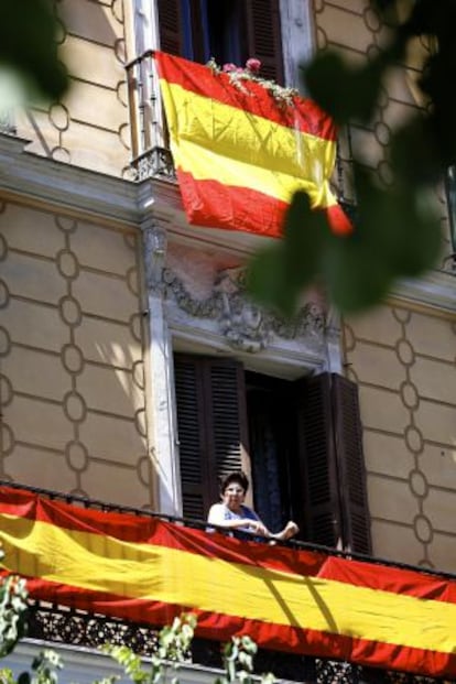 Una vecina de Madrid se asoma al balcón, del que pende la bandera española.