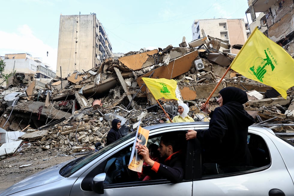 Una mujer con una bandera de Hezbolá pasa con el coche entre los escombros de edificios destruidos por los ataques israelíes en en sur de Beirut, este miércoles.