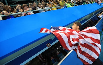 Michael Phelps muestra la bandera estadounidense a su prometida y su hijo.