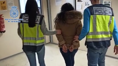 Dos agentes conducen a comisaría a la mujer de 23 años detenida por abandono de menores en Madrid.