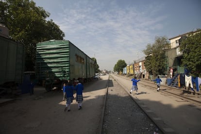 Los niños corren durante su tiempo de recreo por las vías del tren, por donde circulan también otros vecinos caminando. A ambos lados, se amontona el resto de vagones del ferrocarril, donde siguen viviendo los que en otro tiempo se movían con él.