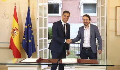 Spain's Prime Minister Pedro Sanchez, centre, shakes hands with the leader of the Podemos party Pablo Iglesias at the Moncloa Palace in Madrid, Spain, Thursday Oct. 11, 2018. Spain's Socialist minority government has agreed with the anti-austerity party Podemos to raise the country's minimum wage and increase taxes for the rich if next year's national budgets get parliamentary approval. Passing the 2019 national budget is seen as a key threshold for Prime Minister Pedro Sanchez's plans to remain in office until the current term ends in 2020. (Fernando Calvo/Pool Photo via AP)