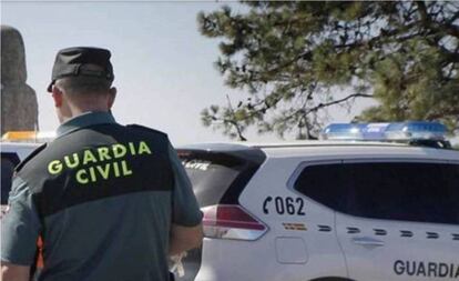 Un guardia civil junto a un coche patrulla.