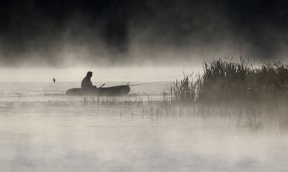 Un hombre pesca desde su bote mientras la niebla le rodea, en el lago de la aldea de Logoisk, al norte de Minsk (Bielorrusia).