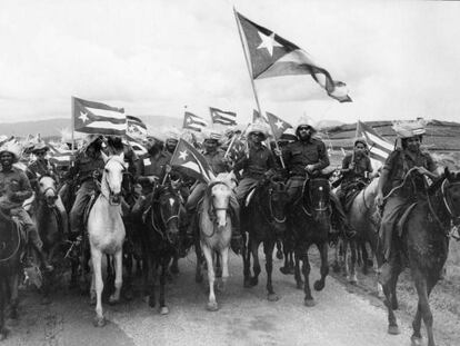 El revolucionario Camilo Cienfuegos porta una gran bandera de Cuba en una marcha de campesinos en 1959. 