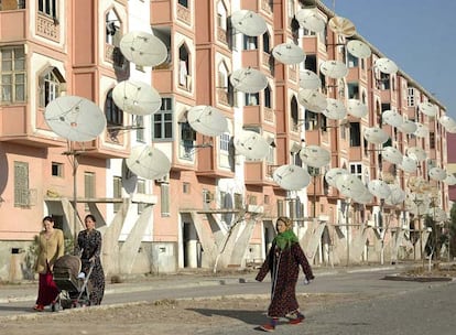 Unas mujeres pasean por delante de un edificio de viviendas plagado de antenas parabólicas en Turkmenabat.