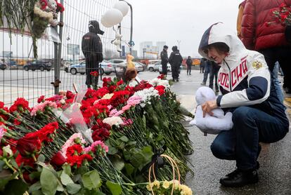 Una mujer deposita un oso de peluche en el homenaje a las víctimas del atentado de la sala Crocus