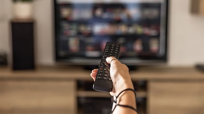 Una persona cambiando el canal en una televisión con un mando universal.