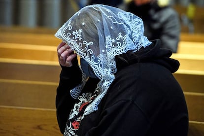 Una mujer reza en una iglesia.