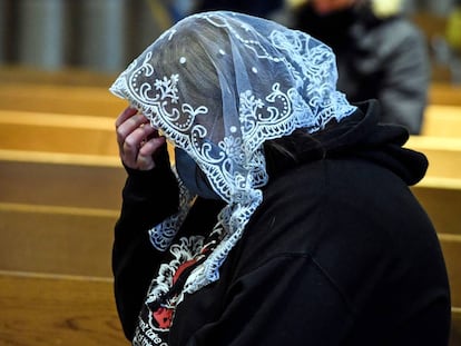 Una mujer reza en una iglesia.