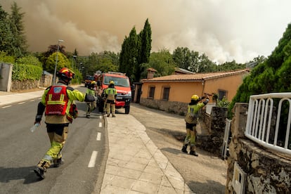Bomberos participan en las labores de evacuación de los vecinos próximos al incendio en Hervás (Cáceres), este domingo.