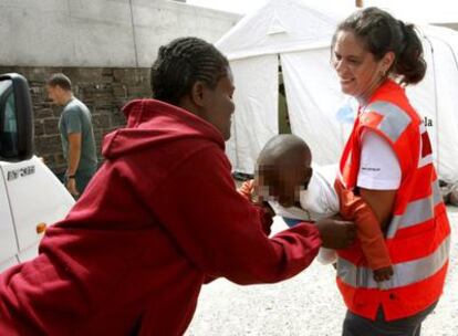 Una voluntaria de la cruz roja juega con uno de los bebé que han llegado hoy en una patera a Tarifa.