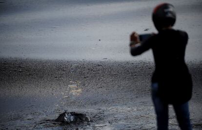 Un hombre indio toma fotografías con su teléfono móvil del chapapote que cubre la playa de Kamarajar, tras la colisión de un barco petrolero en Chennai (India).