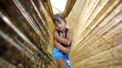 Un niño duerme en una hamaca de tela en una carretera de Nueva Delhi (India).