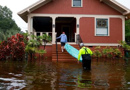 David Rudd ayuda a Steve Odom a llevar un kayak a su porche a través de las calles inundadas por el paso del huracán 'Idalia' en Tarpon Springs, Florida. Se teme que el temporal cause una subida del agua del mar de hasta 4,9 metros de altura.