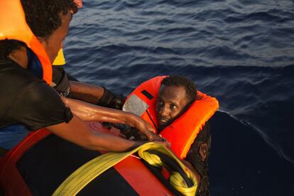 Un eritreo recibe ayuda para subir al bote salvavidas, a 13 kilómetros de la costa libia.