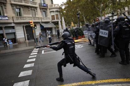 Un agent de la Policia Nacional dispara una bala de goma contra la gent que intenta arribar a un centre de votació.