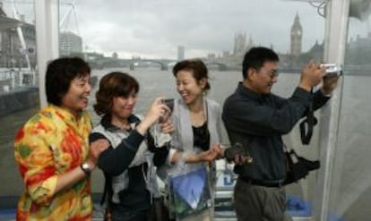 Turistas chinos toman fotograf&iacute;as durante su navegaci&oacute;n por el T&aacute;mesis de Londres.